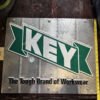 vintage metal advertising sign for KEY Apparel "The Tough Brand of Workwear"